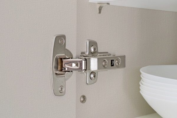 A fitted door hinge inside a white kitchen cupboard