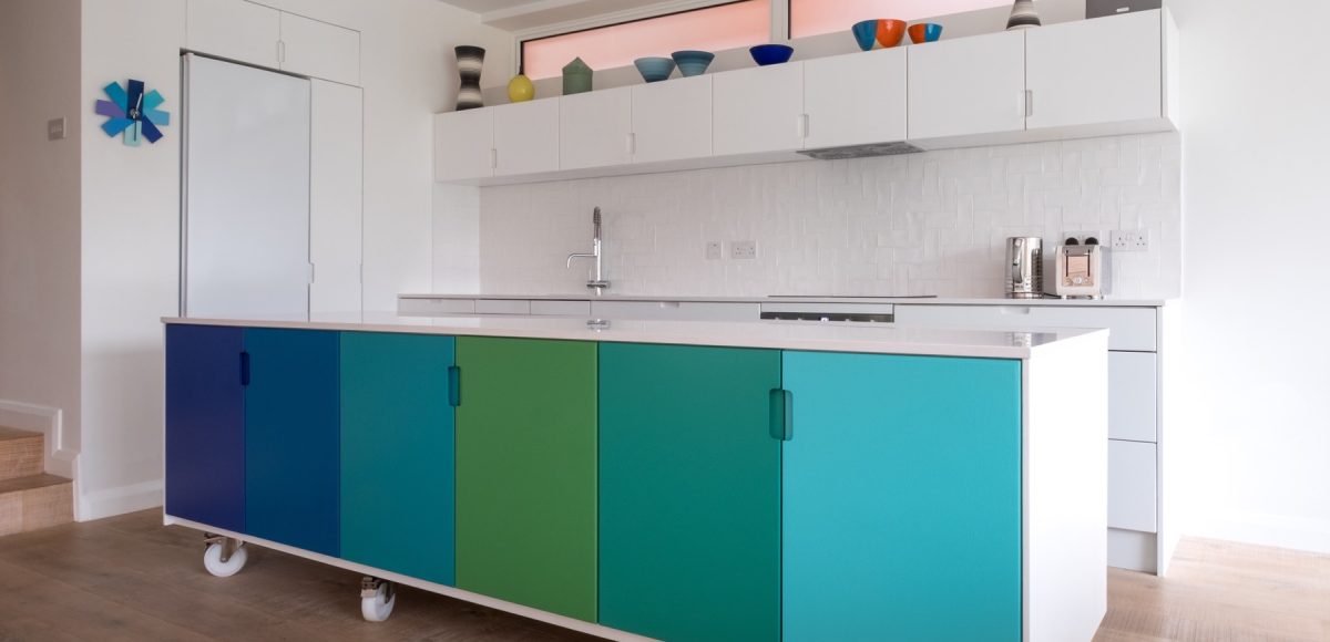 Custom designed kitchen island in painted MDF, in open plan kitchen on industrial castor wheels, retro design painted in blue and green ombre colours.